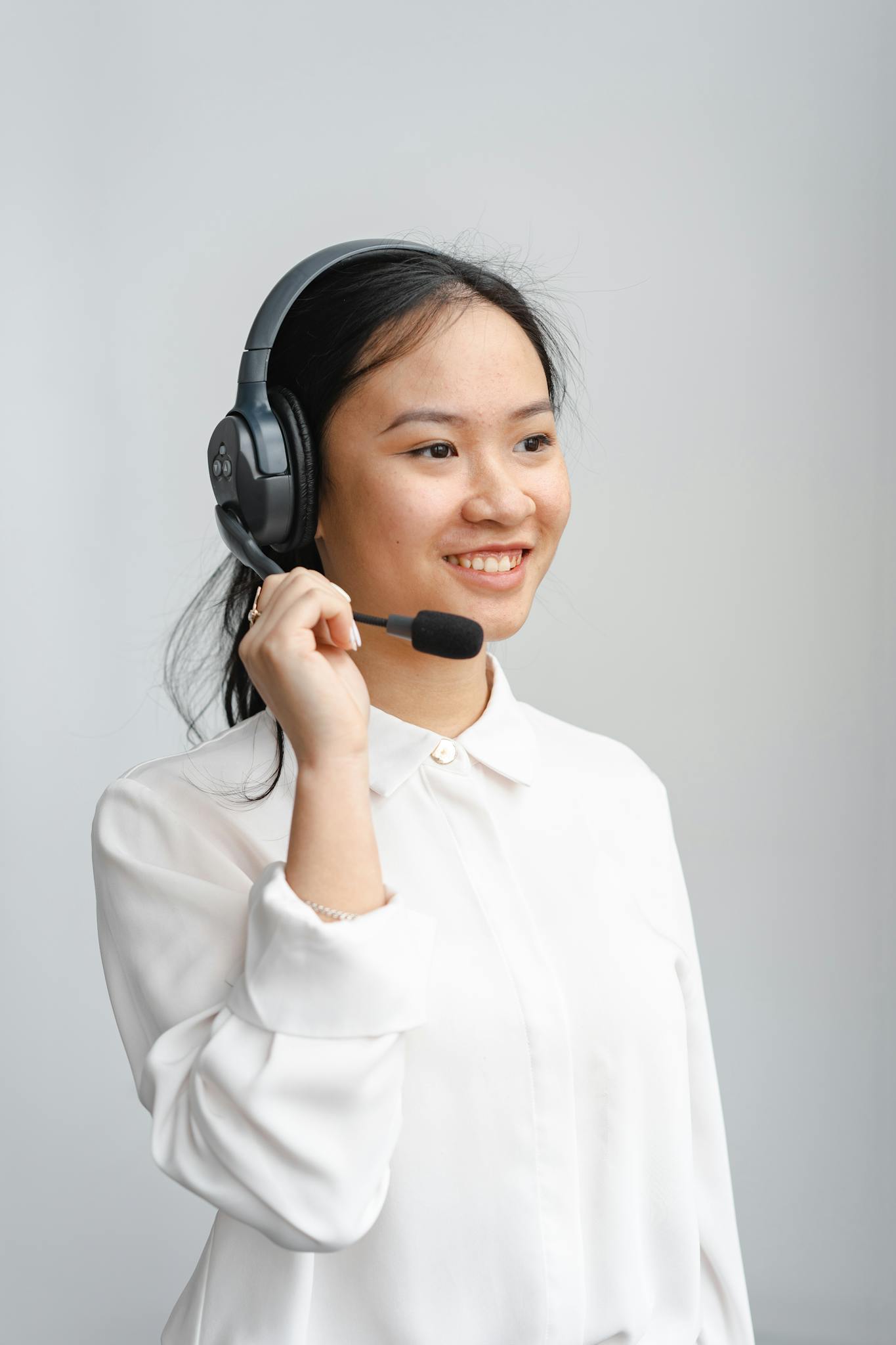 Portrait of a young woman with headphones, providing customer service indoors.