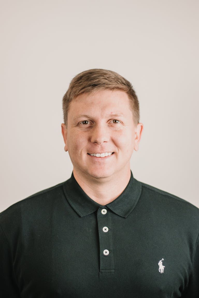 A polished headshot of a smiling man in a dark polo shirt, ideal for business or personal use.