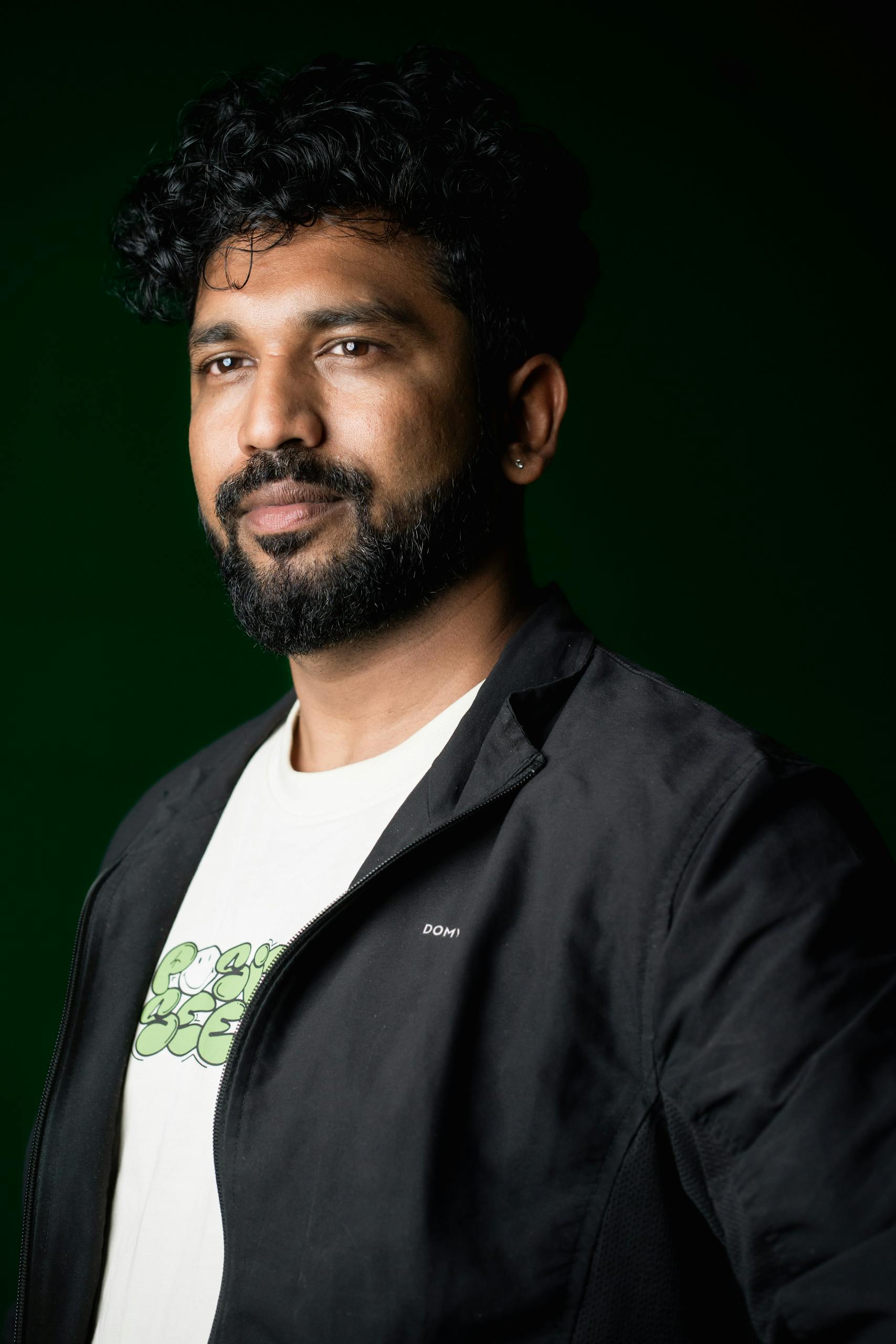 Closeup studio portrait of a thoughtful man with a green background.