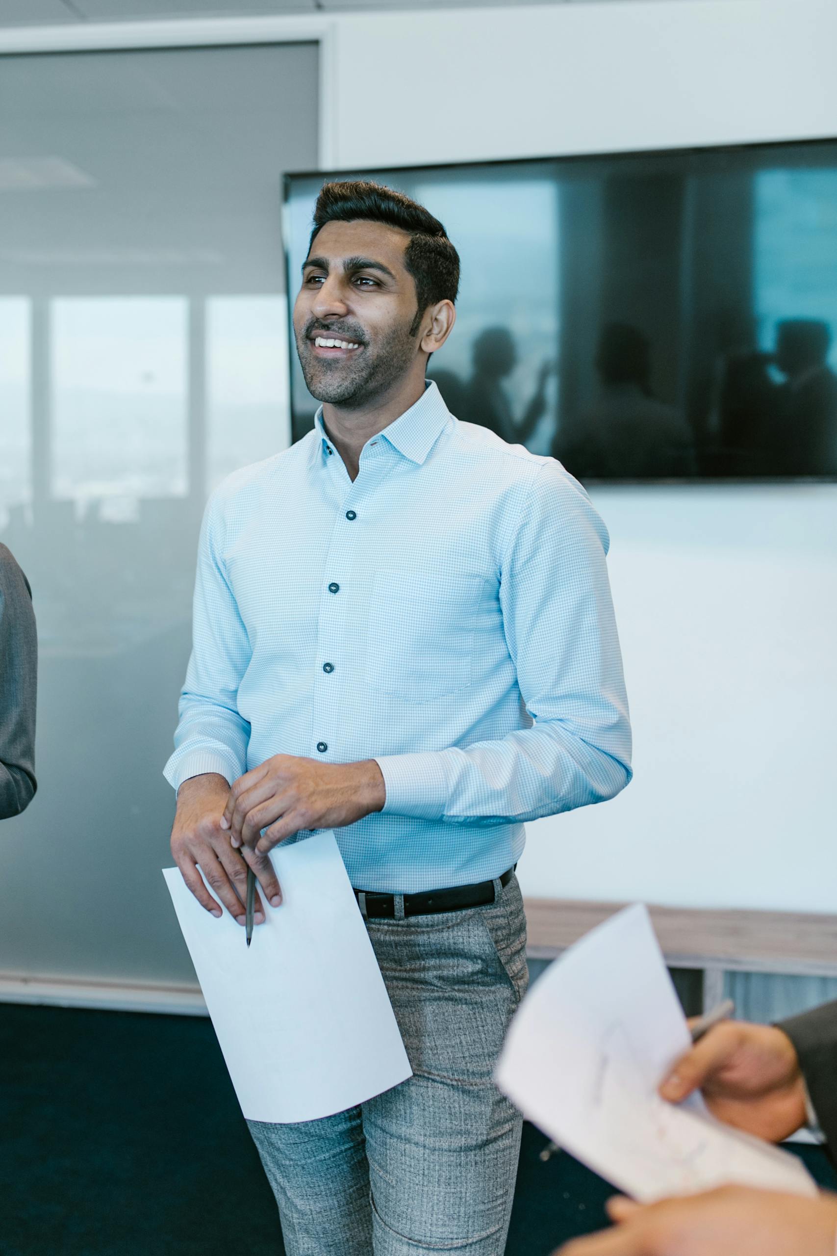 Smiling businessman holding papers during an office meeting.