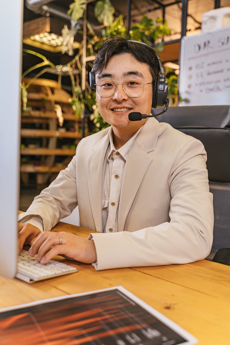 Smiling man with headset working at computer in a stylish office environment.