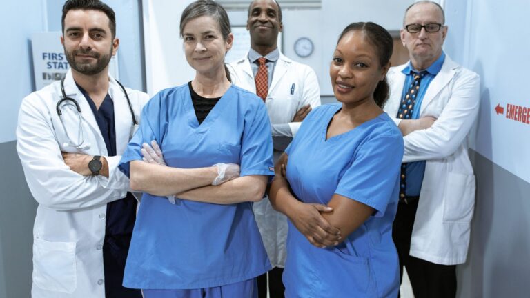 A diverse team of nurses and physicians standing together in a hospital corridor, illustrating exempt and nonexempt healthcare roles