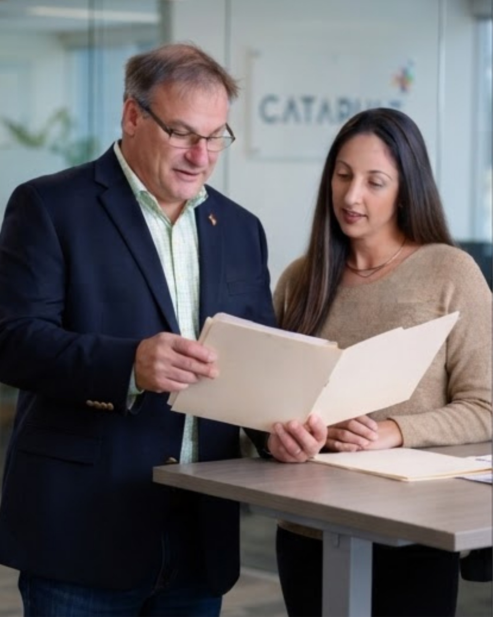 Two Catapult background screening specialists reviewing a candidate file together in the Catapult office