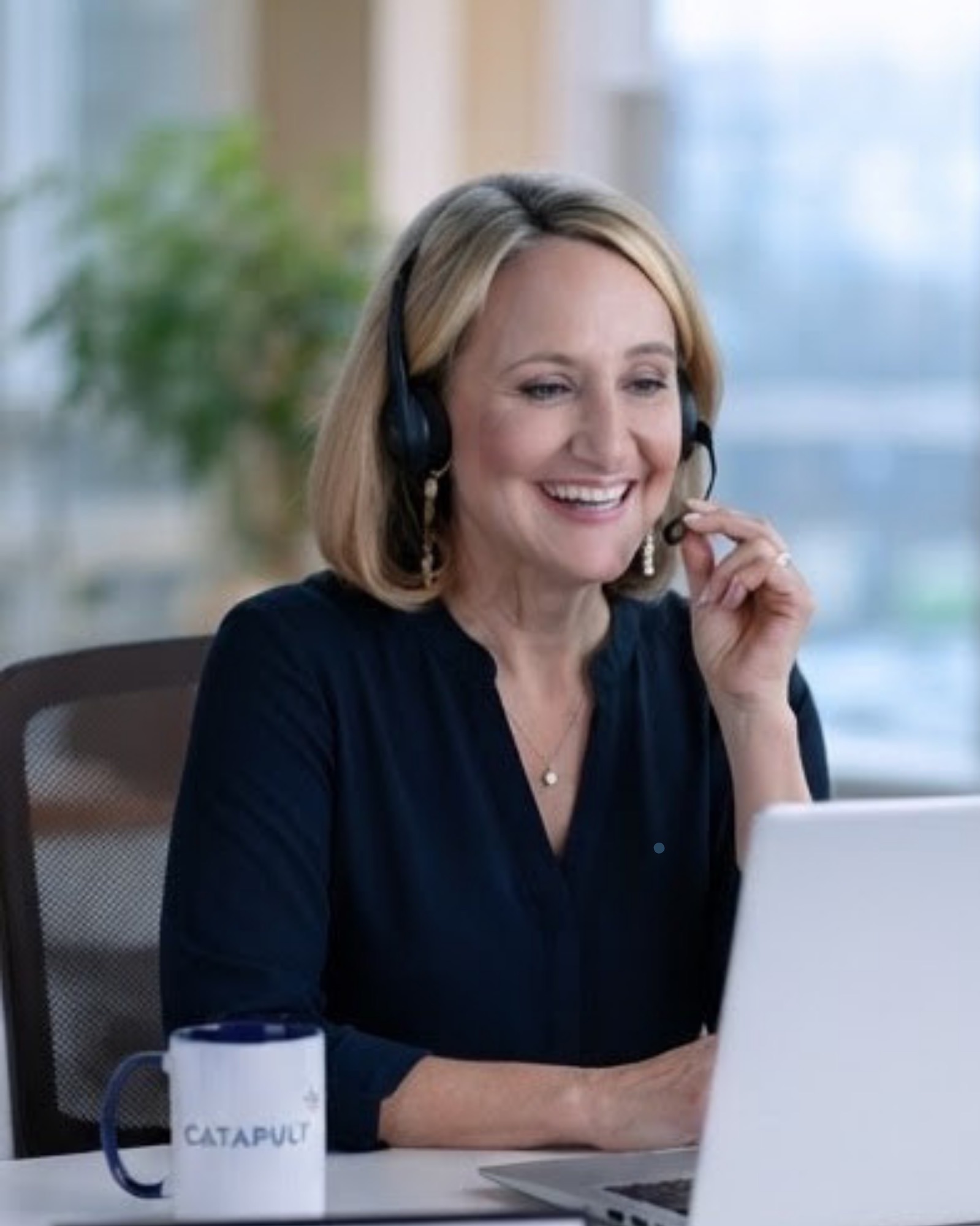A Catapult HR advisor wearing a headset, smiling while helping a member on a call